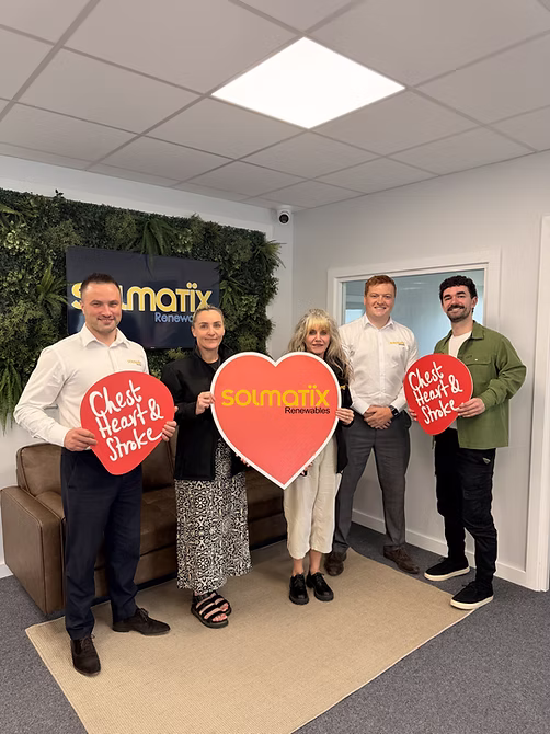 Team photo of Solmatix employees holding red circular promotional signs indoors.