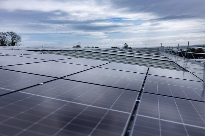 High-angle view across a large commercial rooftop solar panel array under a cloudy sky.