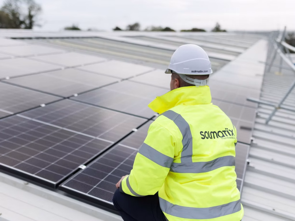 Solar technician wearing a high-visibility vest inspecting a rooftop solar installation.
