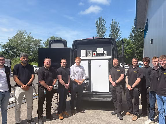 Group of staff standing outdoors near a vehicle.