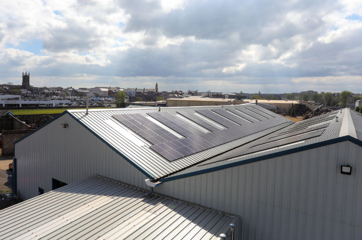 High-angle view looking down across rows of solar panels mounted on a commercial roof.