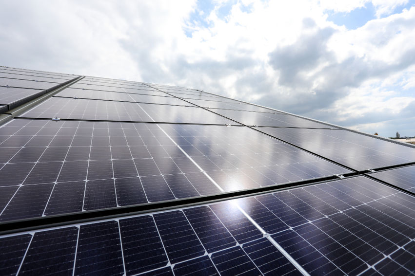 Solar panel array reflecting light clouds on a commercial metal roof.