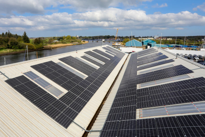 Close-up perspective shot of solar panels installed along a metal roof ridge.