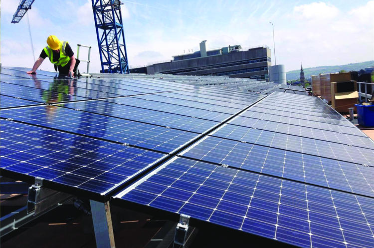 High-angle shot of a commercial rooftop solar panel array with a construction crane in the background.