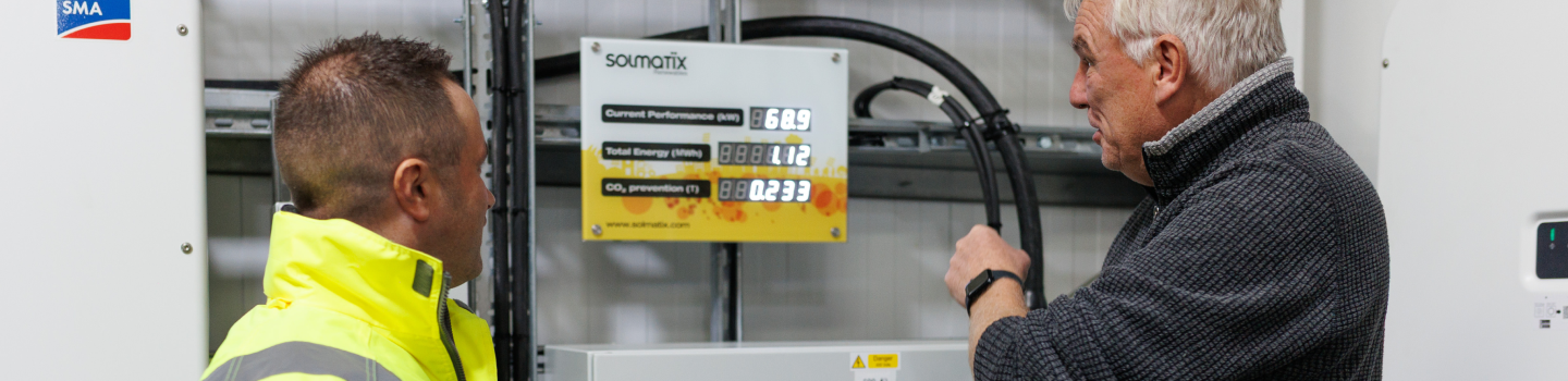 Close-up of a technician interacting with a wall-mounted solar monitor system.