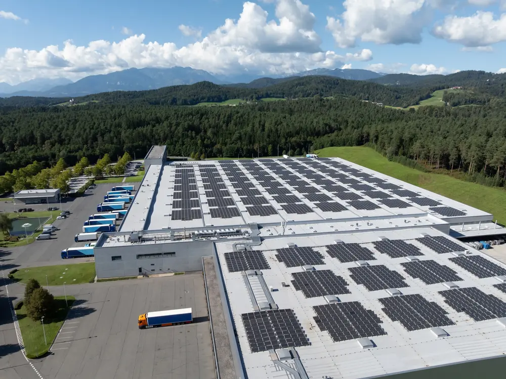 Rooftop solar panel installation on a commercial structure overlooking countryside landscape.