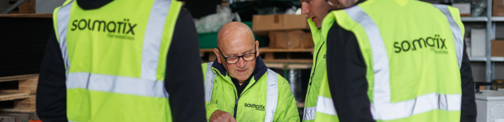 Office colleagues wearing high-visibility vests reviewing web or project plans together.