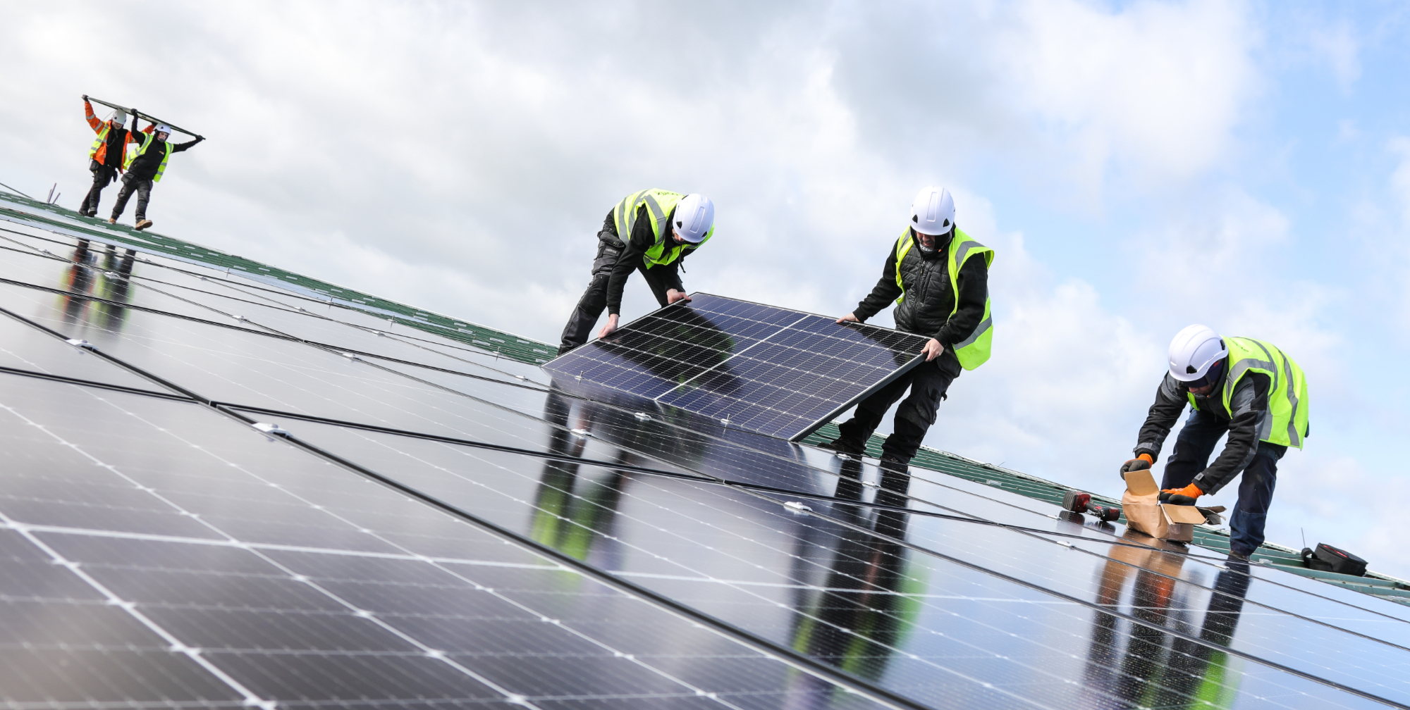 Five workmen with hard hats and high vis installing solar panels