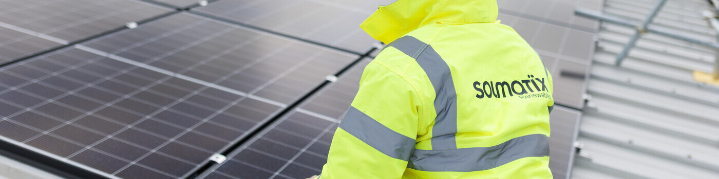Work man with high vis and hardhat looking at Solar panels