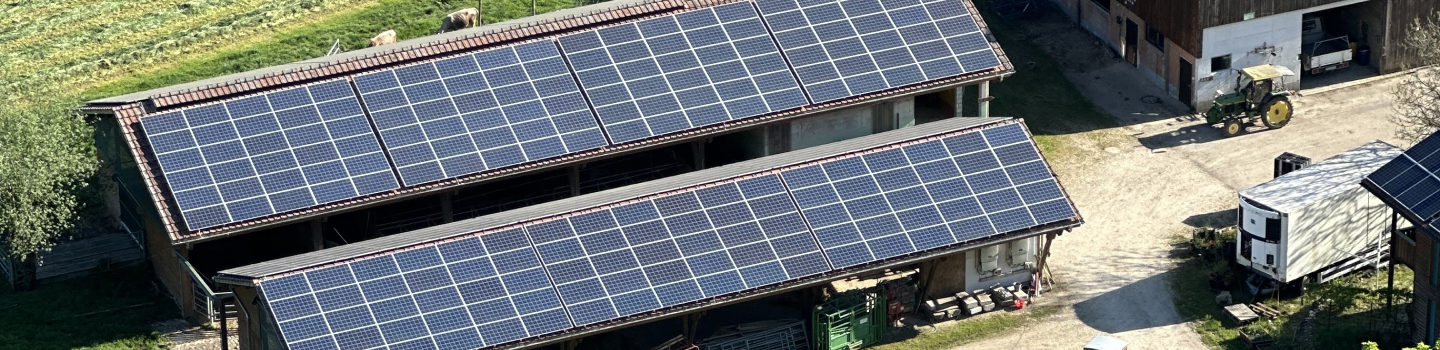 High-angle perspective view of a rooftop solar panel installation on an agricultural building.