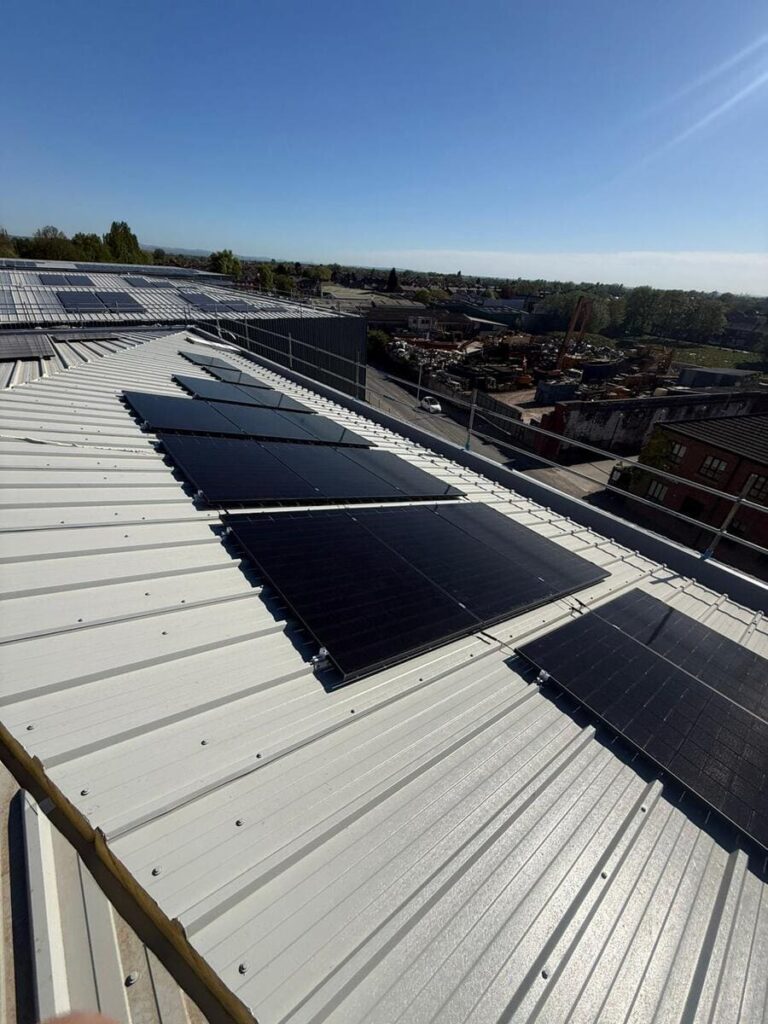 Elevated perspective shot of solar panel arrays mounted on a metal industrial rooftop overlooking a suburban area.
