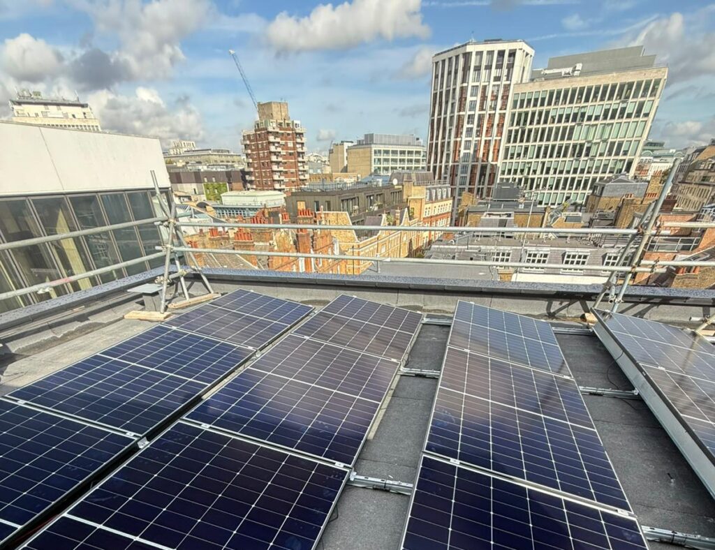 Solar panel installation on a flat roof with city skyline views in the background.