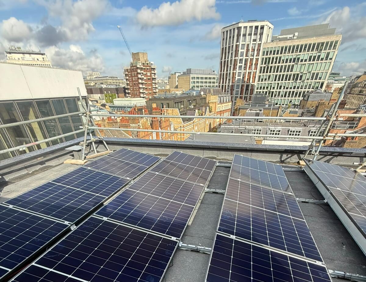 Solar panel installation on a flat roof with city skyline views in the background.