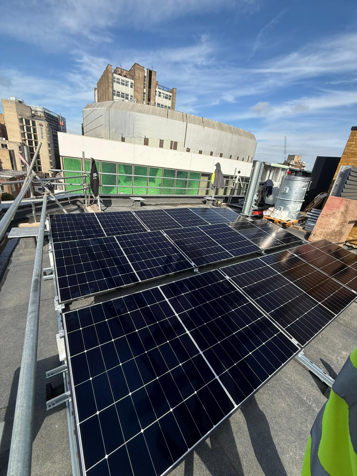 High-angle shot of a commercial solar array installed on a city building roof.