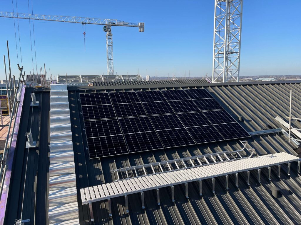 Commercial solar installation on a flat roof overlooking urban developments.
