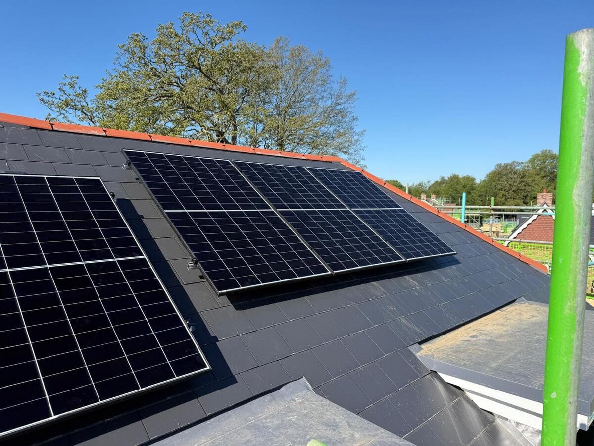 Close-up view of dark solar panel modules fitted onto a slate roof tile surface.