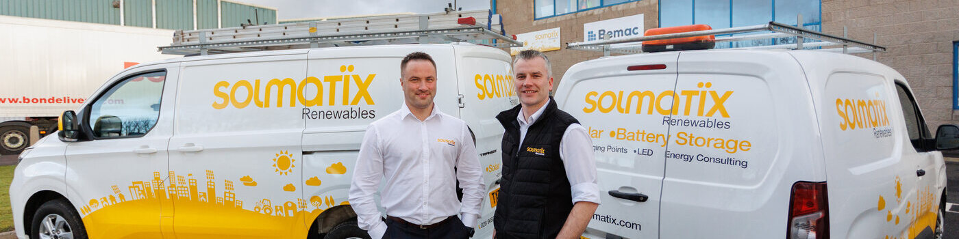Two staff members standing beside branded work vans.
