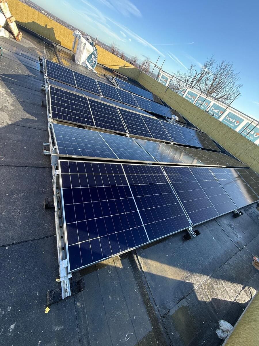 Close-up perspective view along a row of solar panel arrays mounted on a rooftop rack.