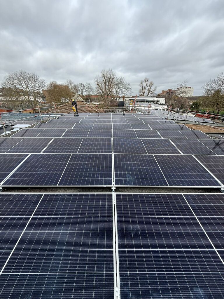 Direct view across a large commercial solar panel array installed flat on a building roof.