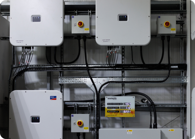 Electrical installation featuring wall-mounted solar inverters and conduit wiring in an equipment room.