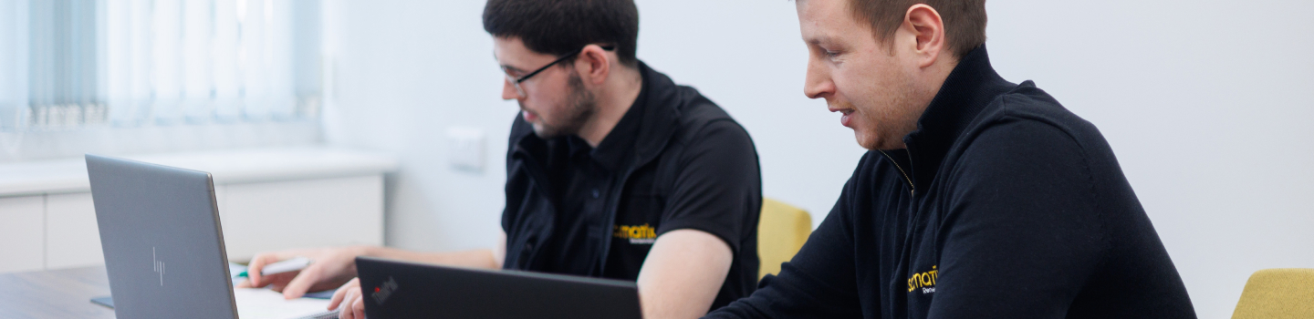 Two support team members seated together reviewing work on a laptop screen.